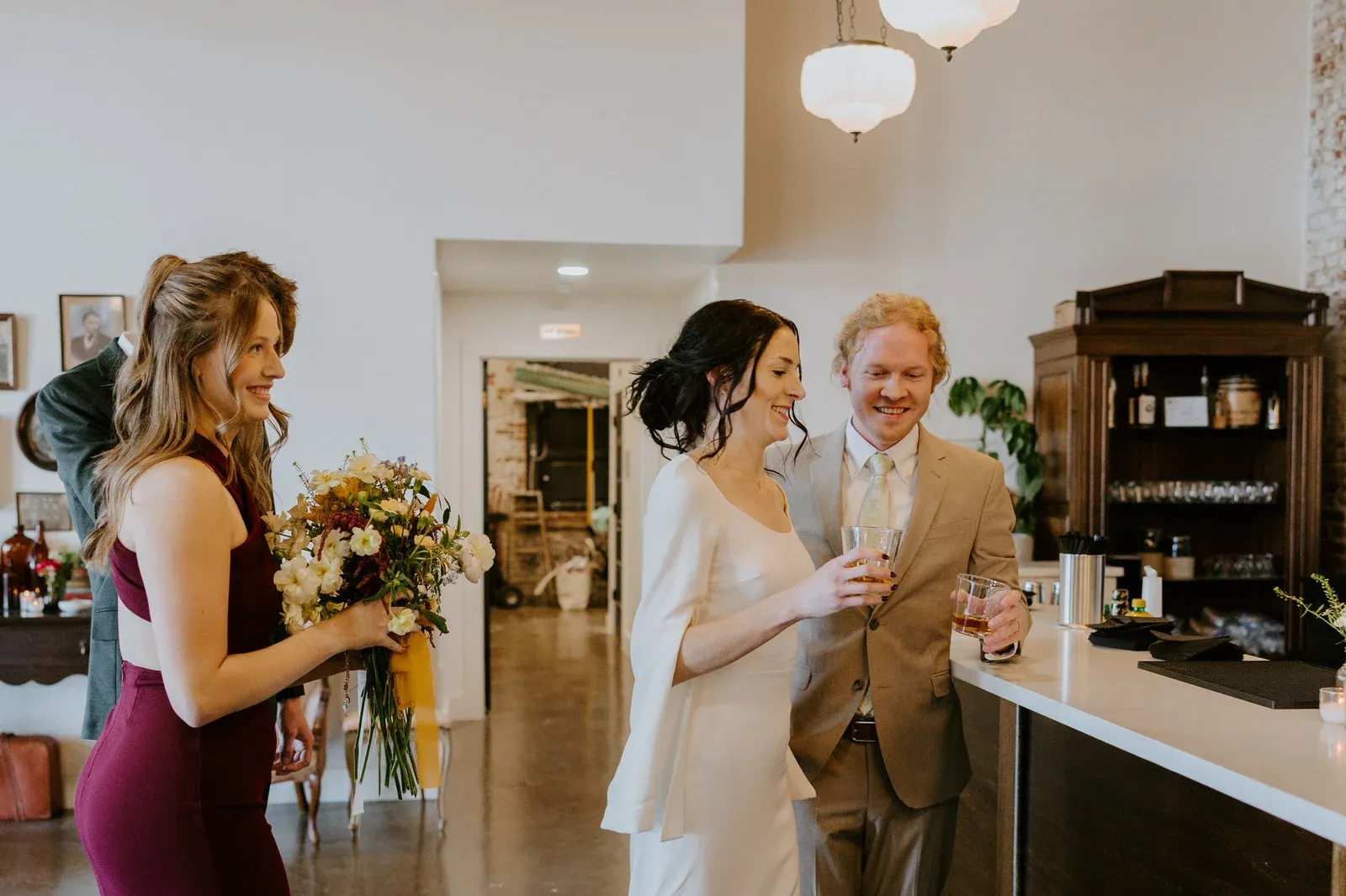 Wedding party and guests cheering with raised glasses at an Indianapolis wedding reception under Edison string lights at 24 Shelby