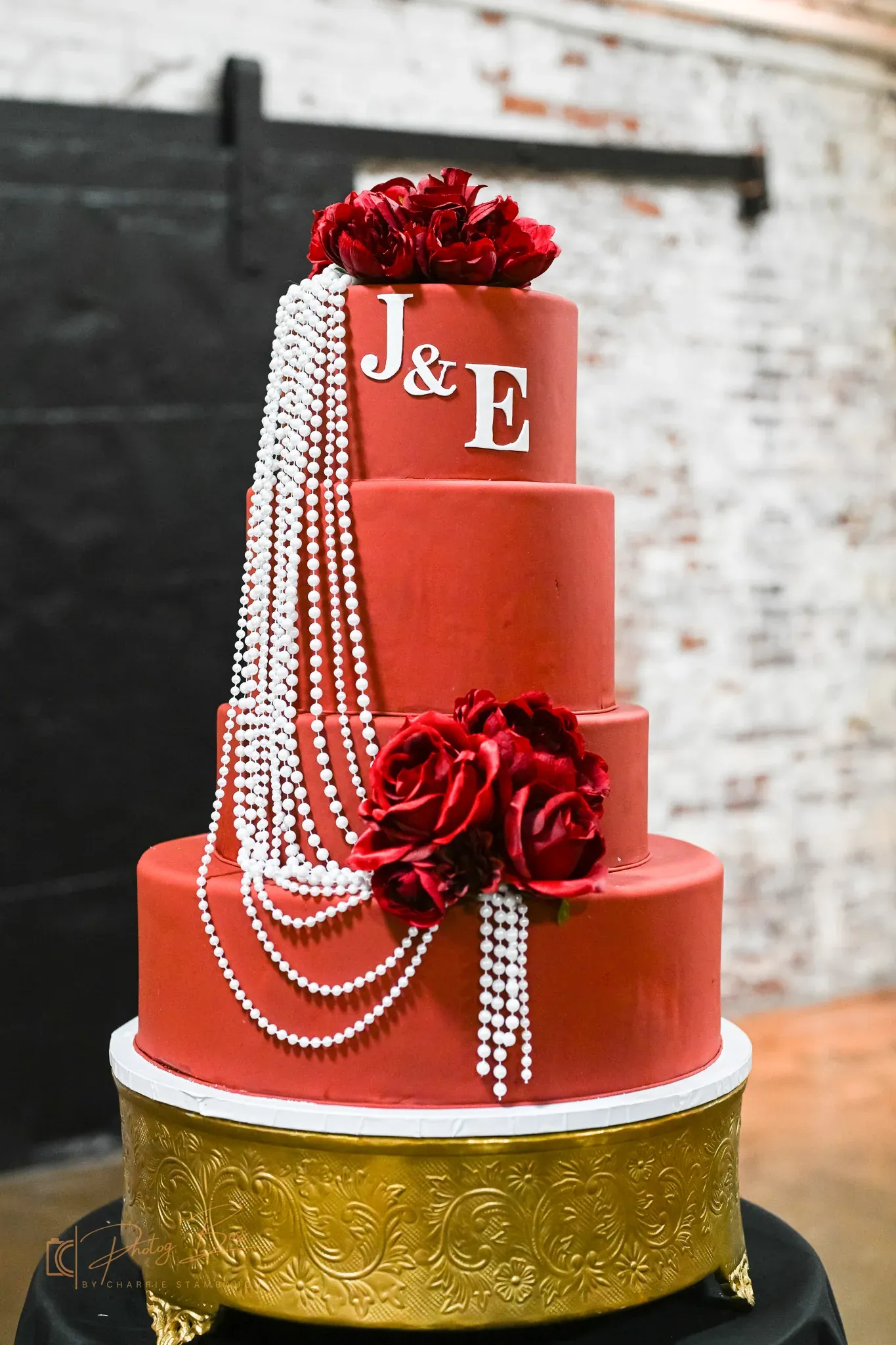 Custom four-tier red wedding cake with monogram, white pearl strands, and red rose accents at a 24 Shelby Indianapolis wedding, illustrating 2026 progressive dining and personalized dessert trends