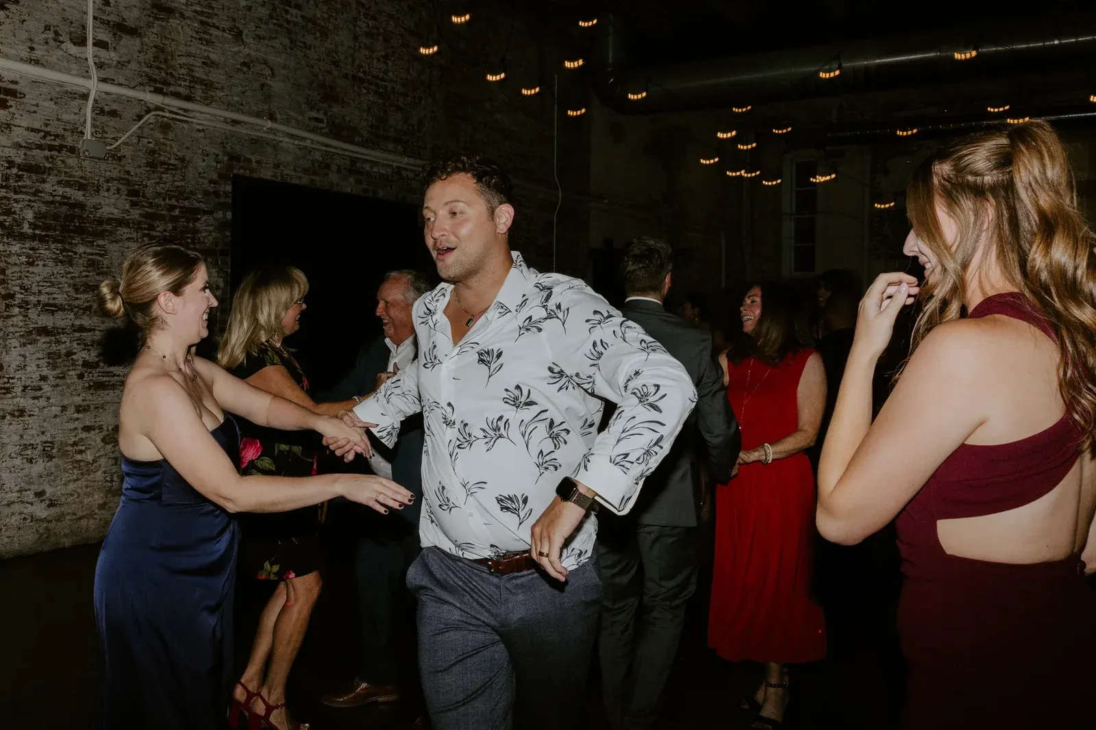Guests dancing under Edison string lights at 24 Shelby, the last-hour dance floor finale of a holiday party in downtown Indianapolis