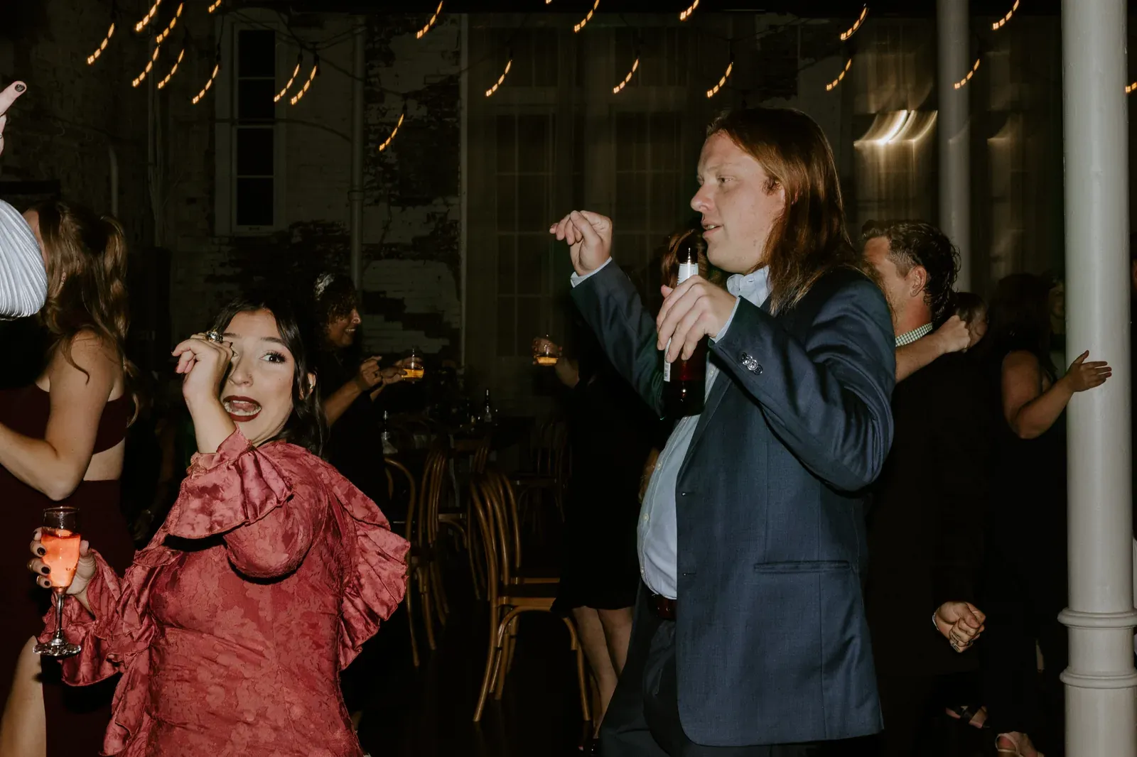 Guests dancing and holding drinks under string lights at an evening party in downtown Indianapolis