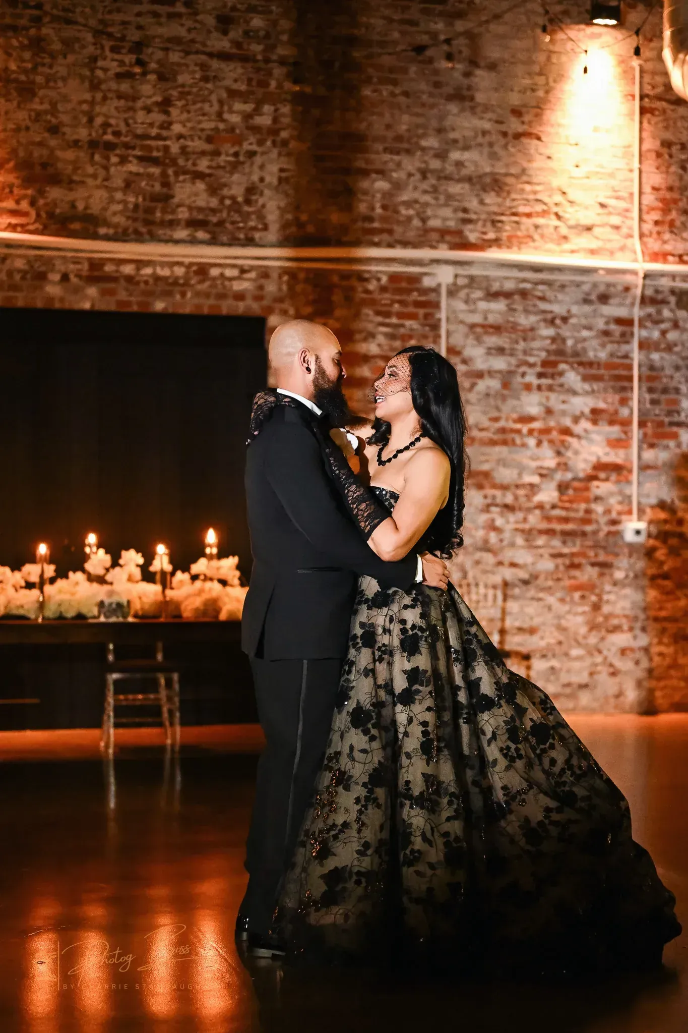 Couple shares an intimate first dance under warm string lights at 24 Shelby with original 1898 brick walls, illustrating the 2026 Indianapolis trend toward experience-driven multi-day wedding weekends