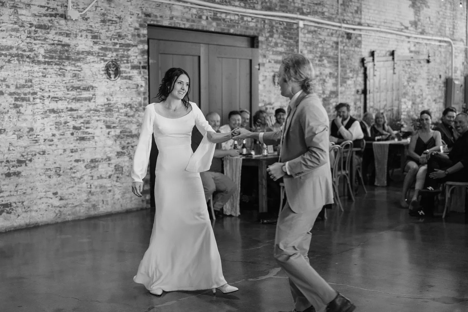 Marin and Chandler's first dance at 24 Shelby against original 1898 exposed brick walls under warm Edison string lights at their downtown Indianapolis wedding