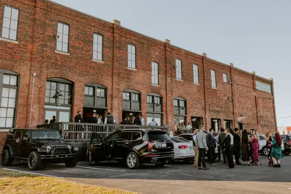Newlywed couple on the Prohibition Patio at 24 Shelby, an indoor-outdoor wedding venue in Indianapolis, framed by the original 1898 brick facade and the open garage door leading back into the Edison Room.