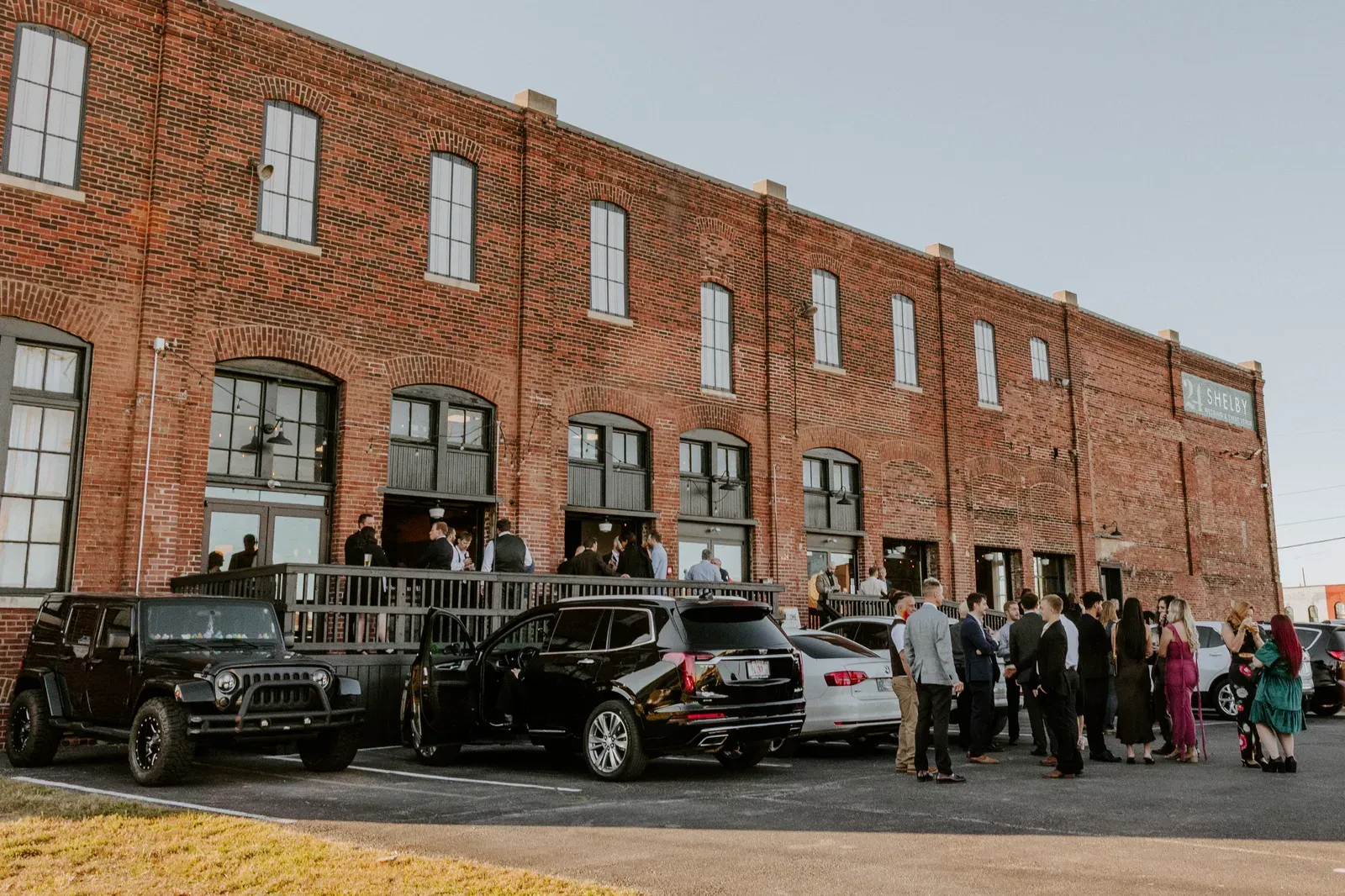 Newlywed couple on the Prohibition Patio at 24 Shelby, an indoor-outdoor wedding venue in Indianapolis, framed by the original 1898 brick facade and the open garage door leading back into the Edison Room.