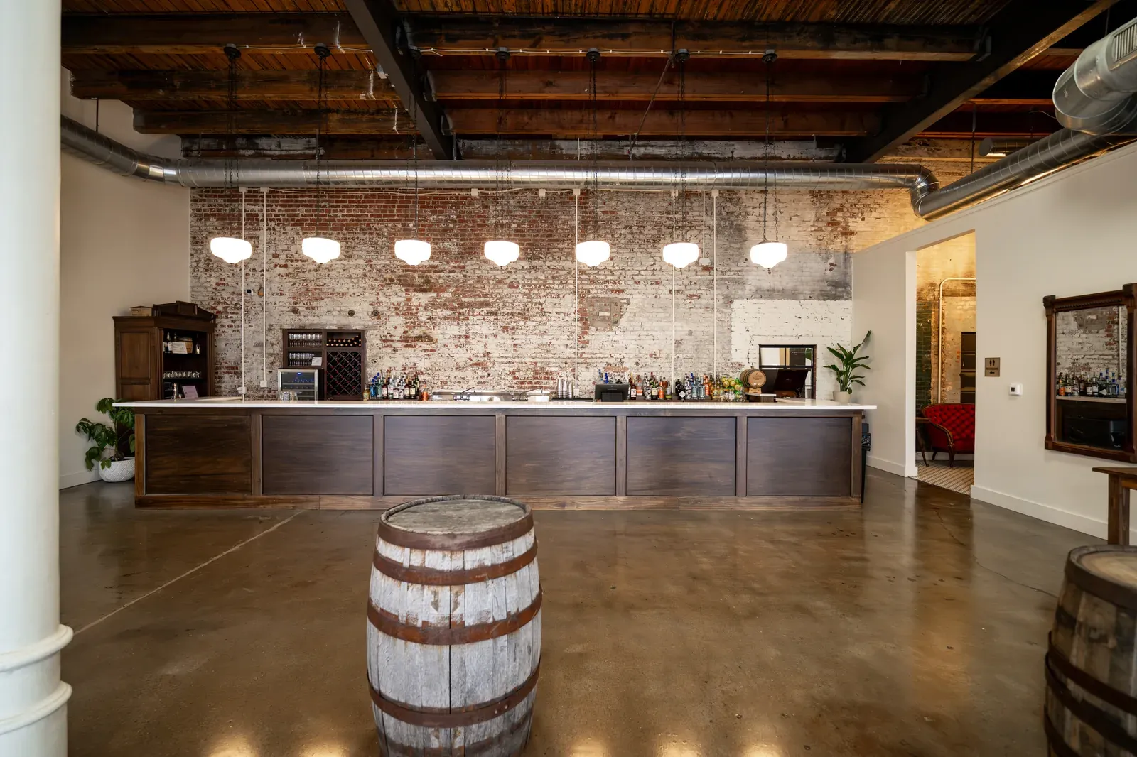 The Libations Lounge bar at 24 Shelby with exposed brick, whiskey barrels, and pendant lighting