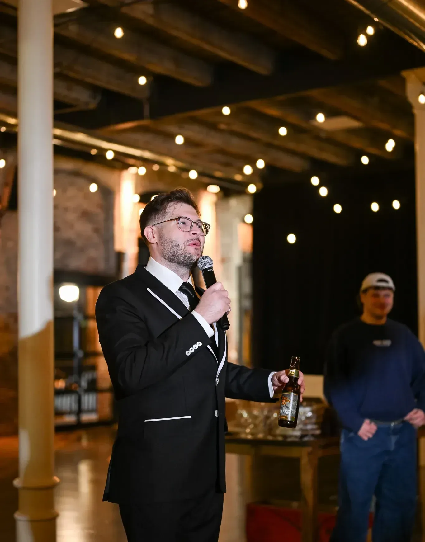 Speaker presenting at a corporate event inside 24 Shelby in downtown Indianapolis under Edison lighting and exposed 1898 brick walls