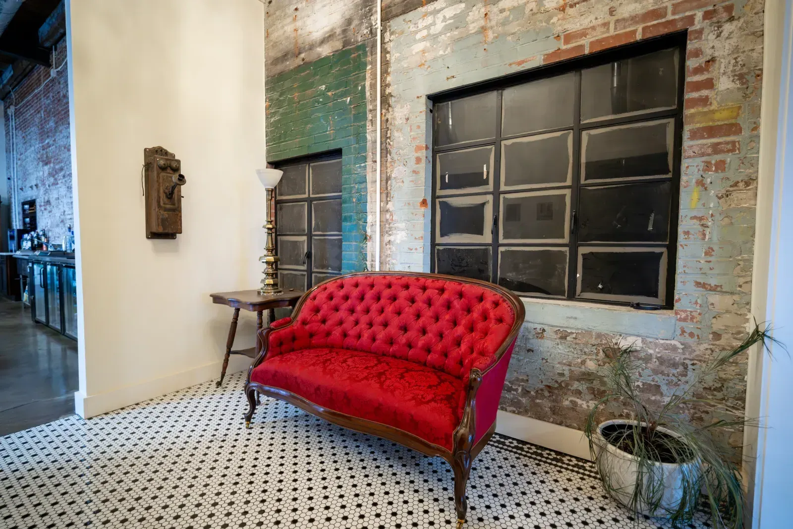 The red velvet settee and black-and-white hex tile in the lounge at 24 Shelby against original 1898 brick, the natural setting for a speakeasy holiday party theme in Indianapolis