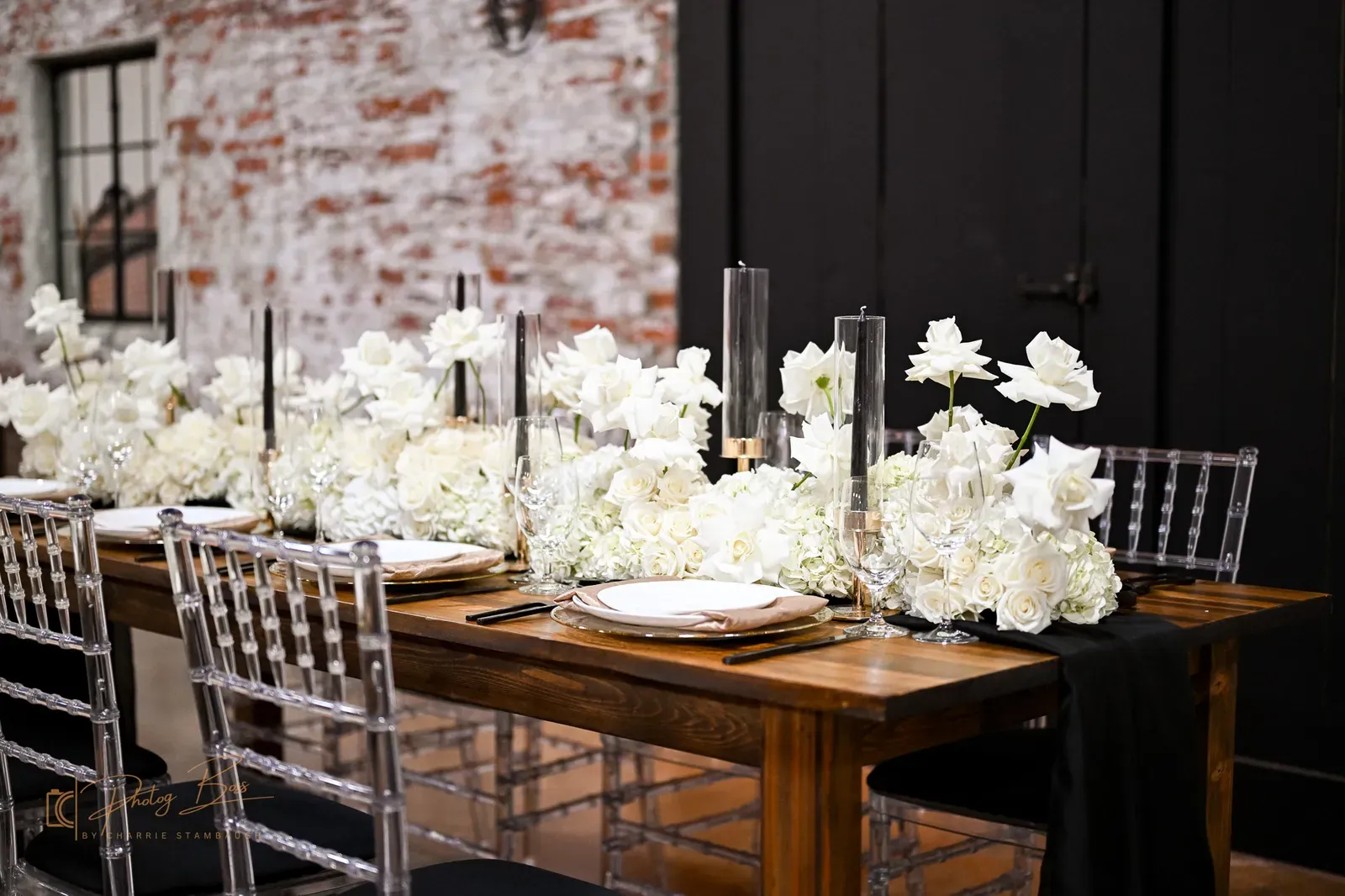 Detail of an Indianapolis wedding reception tablescape at 24 Shelby with florals, glassware, and place settings on a wood farm table against original exposed brick