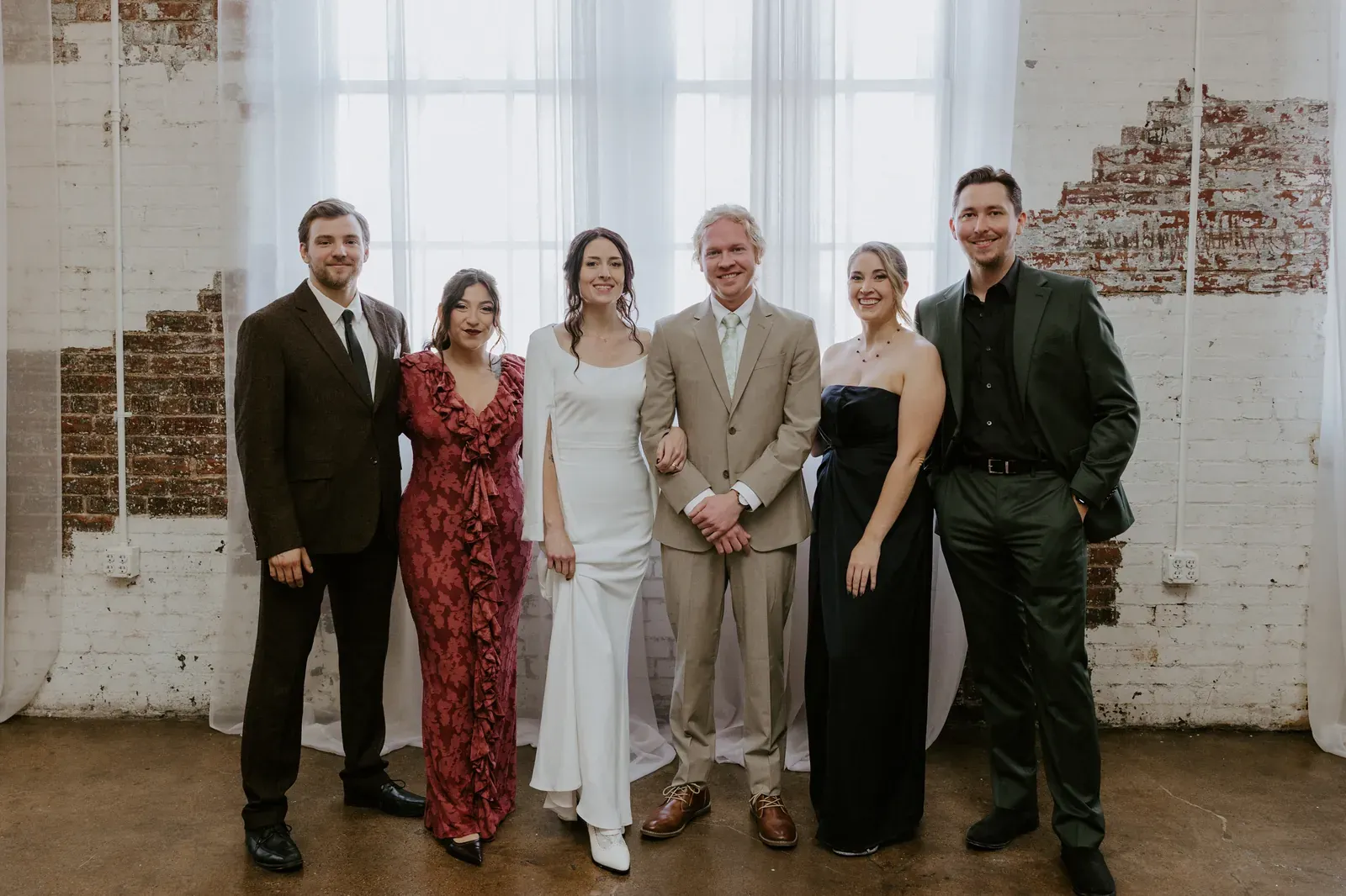 Wedding party portrait against 24 Shelby's white-painted brick wall and natural light from oversized original windows